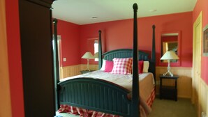 Een kamer met rode wanden en een houten vloer, waarin een bed met vier pilaren staat.