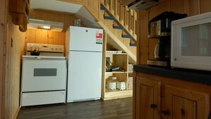 Una cocina con armarios de madera, una estufa blanca, un refrigerador y un microondas.