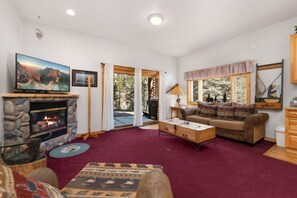 A cozy living room with a fireplace, a sofa, a coffee table, and a television. - Fall River Hideaway • Private Hot Tub• Near RMNP (Estes Park)