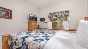 A bedroom with a bed, a wooden dresser, a television, and a window with curtains. - Fall River Hideaway • Private Hot Tub• Close to RMNP (Estes Park)