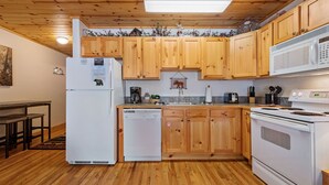 A kitchen with wooden cabinets, a refrigerator, a dishwasher, a microwave, and a stove. - Fall River Hideaway • Private Hot Tub (Estes Park)
