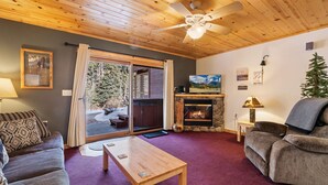 A cozy living room with a fireplace, a sofa, a coffee table, and a ceiling fan. - Fall River Hideaway • Private Hot Tub (Estes Park)