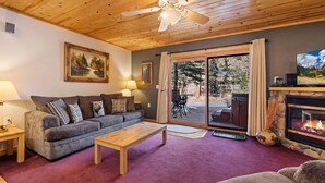 A cozy living room with a grey sofa, wooden coffee table, and a fireplace. - Fall River Hideaway • Private Hot Tub (Estes Park)