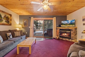 A cozy living room with a fireplace, a sofa, a coffee table, and a television.