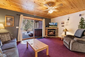 A cozy living room with a fireplace, a television, and a ceiling fan. - Fall River Hideaway • Private Hot Tub (Estes Park)