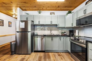A modern kitchen with stainless steel appliances, light grey cabinets, and wooden flooring. - Renovated Fall River Escape • Private Hot Tub (Estes Park)