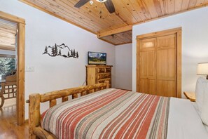 A room with a wooden bed, a wooden wardrobe, and a wall-mounted TV. - Riverfront Escape •Private Hot Tub • Close to RMNP (Estes Park)