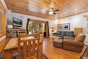 A wooden interior with a dining table, chairs, a sofa, and a television. - Riverfront Escape •Private Hot Tub • Close to RMNP (Estes Park)