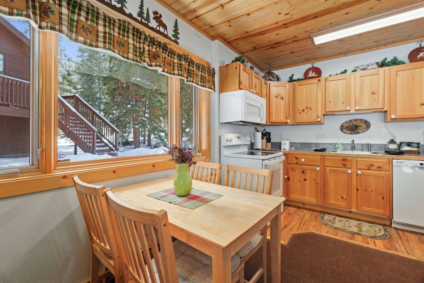 Un intérieur en bois comprenant une table à manger, des chaises, une cuisine avec des meubles en bois, un four à micro-ondes et une cuisinière.