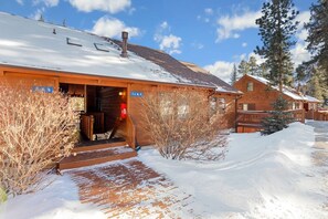 A wooden lodge with a covered entrance and a snow-covered landscape.