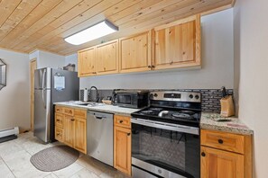 A kitchen with wooden cabinets, stainless steel appliances, a microwave, and a stove.