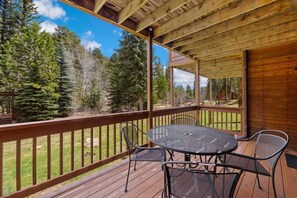 Eine überdachte Terrasse mit Holzgeländer, einem runden Tisch und vier Stühlen.