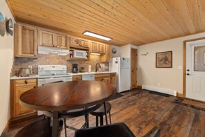 A kitchen with wooden cabinets, a central island, and a dining table. - Riverfront Retreat • Near RMNP • River Views (Estes Park)