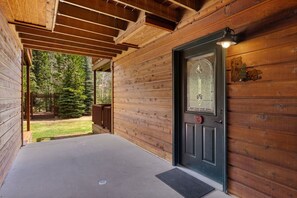 A wooden cabin with a porch, a door with a number, and a view of a forest. - Riverfront Retreat • Near RMNP • River Views (Estes Park)