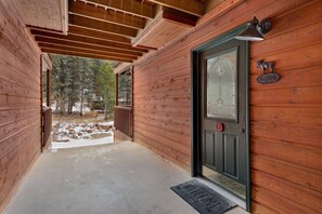 A wooden cabin with a black door, a welcome sign, and a number plate.