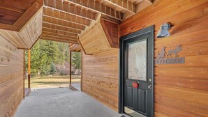 A wooden cabin entrance with a black door, a welcome sign, and a number plaque. - Quiet Fall River Suite • River Views • RMNP (Estes Park)
