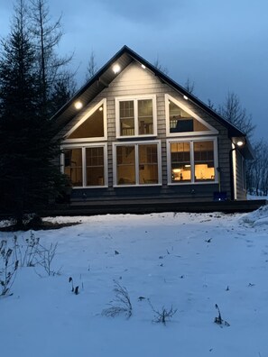 Een herenhuis met een puntgevel, grote ramen en een met sneeuw bedekte grond.