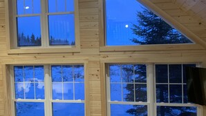 Una cabaña de madera de varios niveles, con amplios ventanales que ofrecen vistas del bosque circundante.