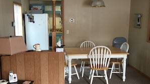 Un espai habitable pràctic amb una cuineta, una zona de menjador amb taula i cadira, i un sofà.