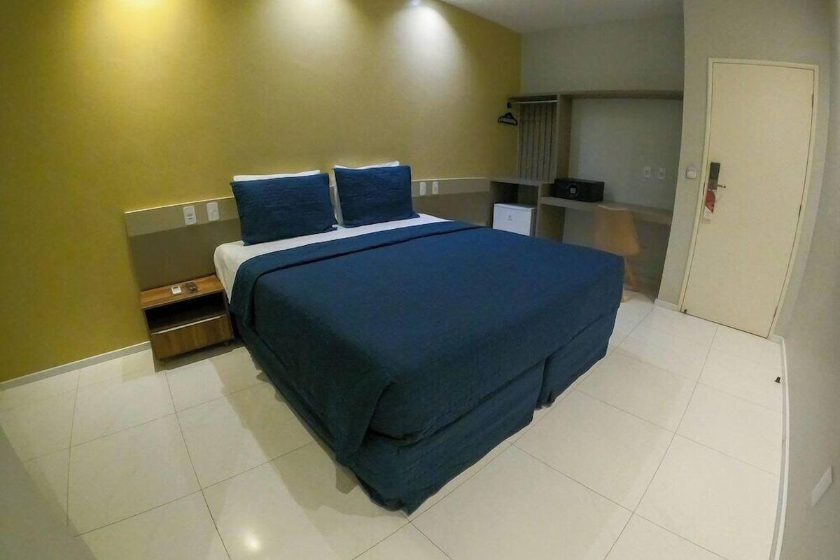 A hotel room with a bed, a nightstand, a wardrobe, and a door.