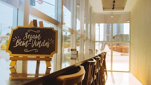 Interior de un restaurante con una larga barra, sillas de madera y un letrero que dice 'Sejam Bem-Vindos'.