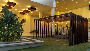 Un jardín interior moderno con una pérgola de madera, zona de estar y plantas en macetas.