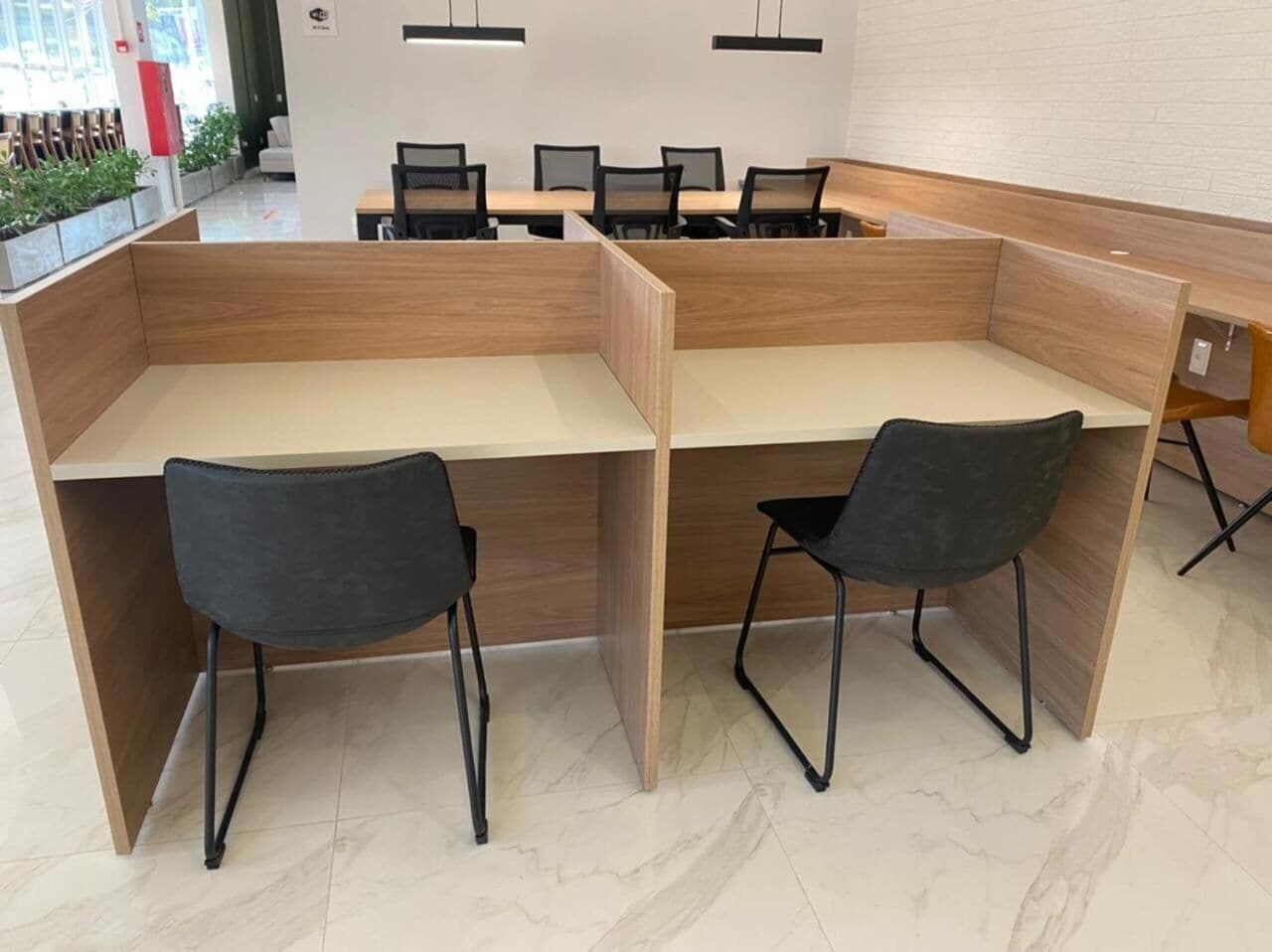 A modern office space with two workstations, each with a black chair and a wooden desk.