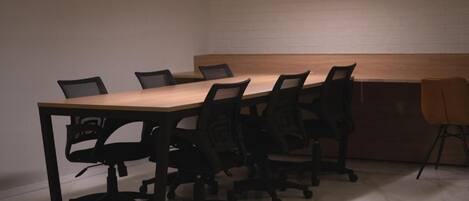 A conference room with a long table, black office chairs, and pendant lighting.