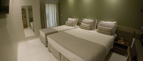 A hotel room with two beds, a flat-screen TV, a bedside table, and a mirror.