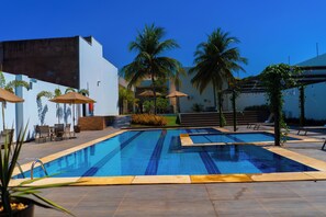 A swimming pool with tiled edges, surrounded by palm trees and outdoor seating. - Nord Luxxor Juazeiro (Juazeiro do Norte)