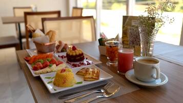 A breakfast setting with a variety of dishes, including pancakes, a fruit salad, and a dessert, along with coffee and juice.