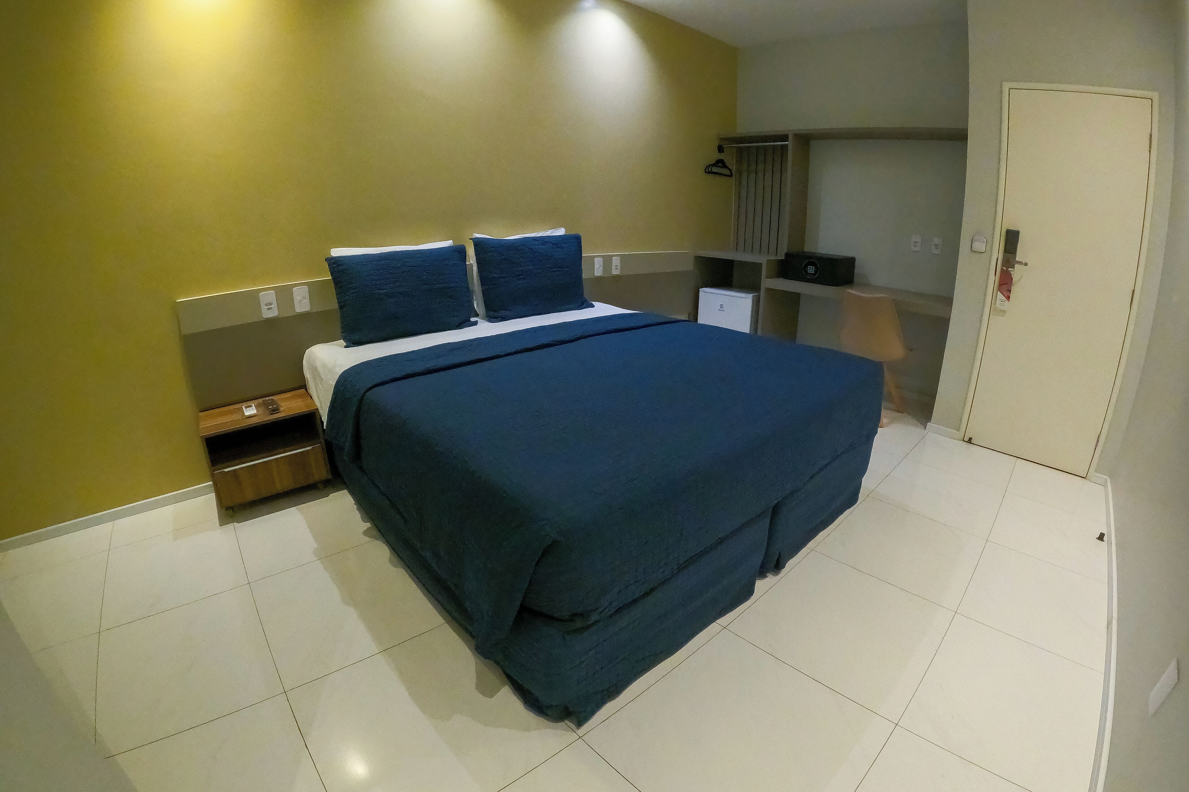 Una habitación de hotel con cama, armario, escritorio y puerta.