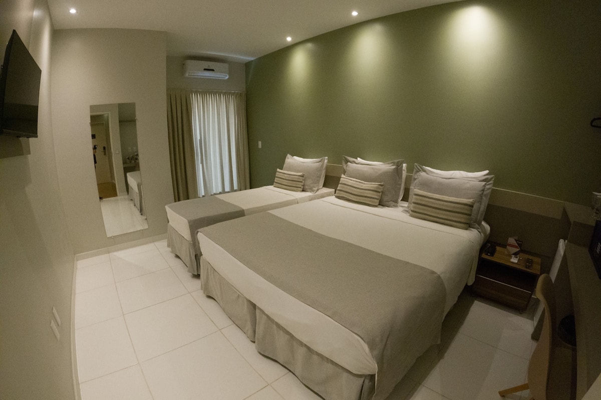 A hotel room with two beds, a TV, a desk, and a chair.