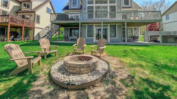 A two-story house with a covered patio, outdoor seating area, and a fire pit. - Amazing Central Location! Lakefront! Hot tub/dock! (Oakland)