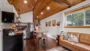 A cozy kitchen with wooden ceiling beams, a black refrigerator, and a wooden dining table with stools. - SUPER CUTE & CLEAN MODERN HOME 40 min. to YNP (Island Park)