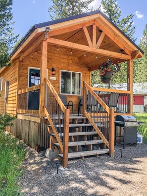 A wooden cabin with a porch, a staircase, and a grill outside. - SUPER CUTE & CLEAN MODERN HOME 40 min. to YNP (Island Park)