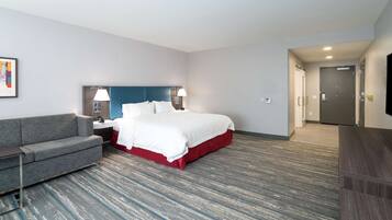 A hotel room with a bed, a sofa, a desk, and a television.