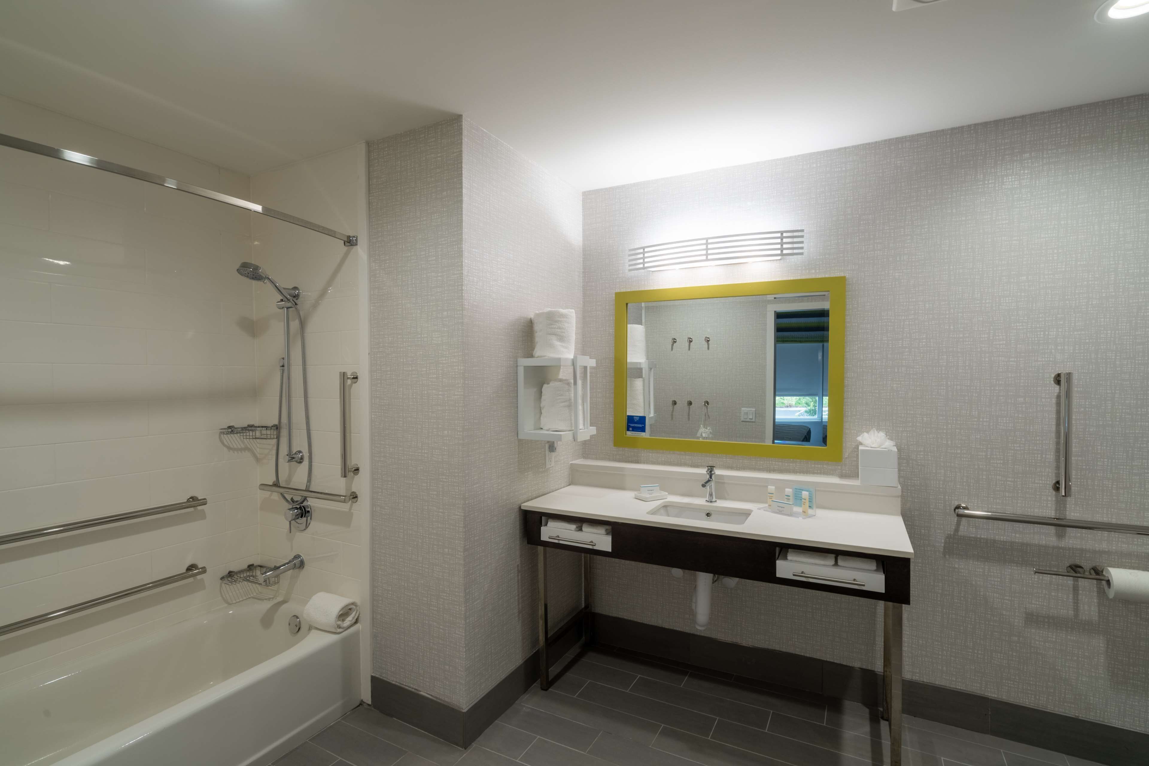 Un baño moderno con bañera, lavamanos, espejo y toallero.