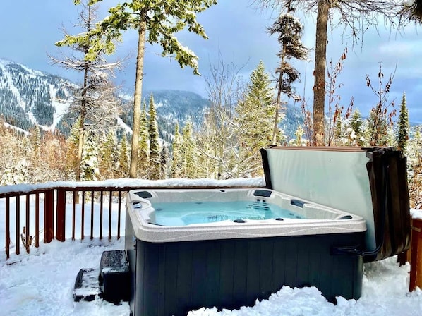 Un jacuzzi en un entorno nevado al aire libre, con vista a la montaña.