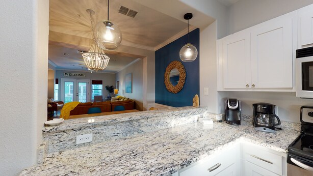 A modern kitchen with white cabinets, a marble countertop, and a coffee maker. - Shared Pool and Hot Tub, Golf Cart Access (Port Aransas)
