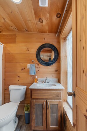 A compact wooden bathroom with a toilet, sink, and cabinet.