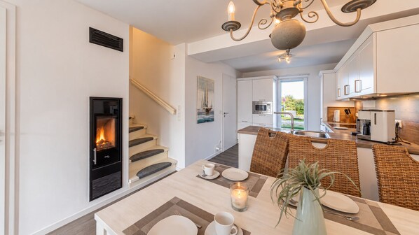 A modern kitchen with white cabinets, a built-in stove, and a dining area with a table set for two.