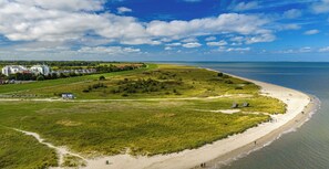 Een kustlandschap met een strand, grasvelden en een weg naar een nederzetting.