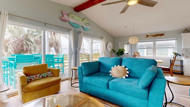 Un salon lumineux avec un canapé turquoise, un fauteuil moutarde et une table basse en bois.