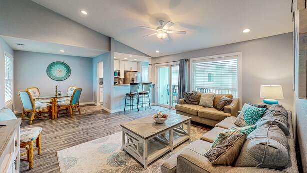 A living room with a sofa, coffee table, and dining area with chairs. - 2nd Floor, Shared Pool, Pet Friendly, Golf Cart Access (Port Aransas)