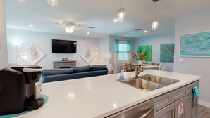 Una cocina moderna con lavavajillas integrado, un fregadero y un comedor con mesa y sillas.