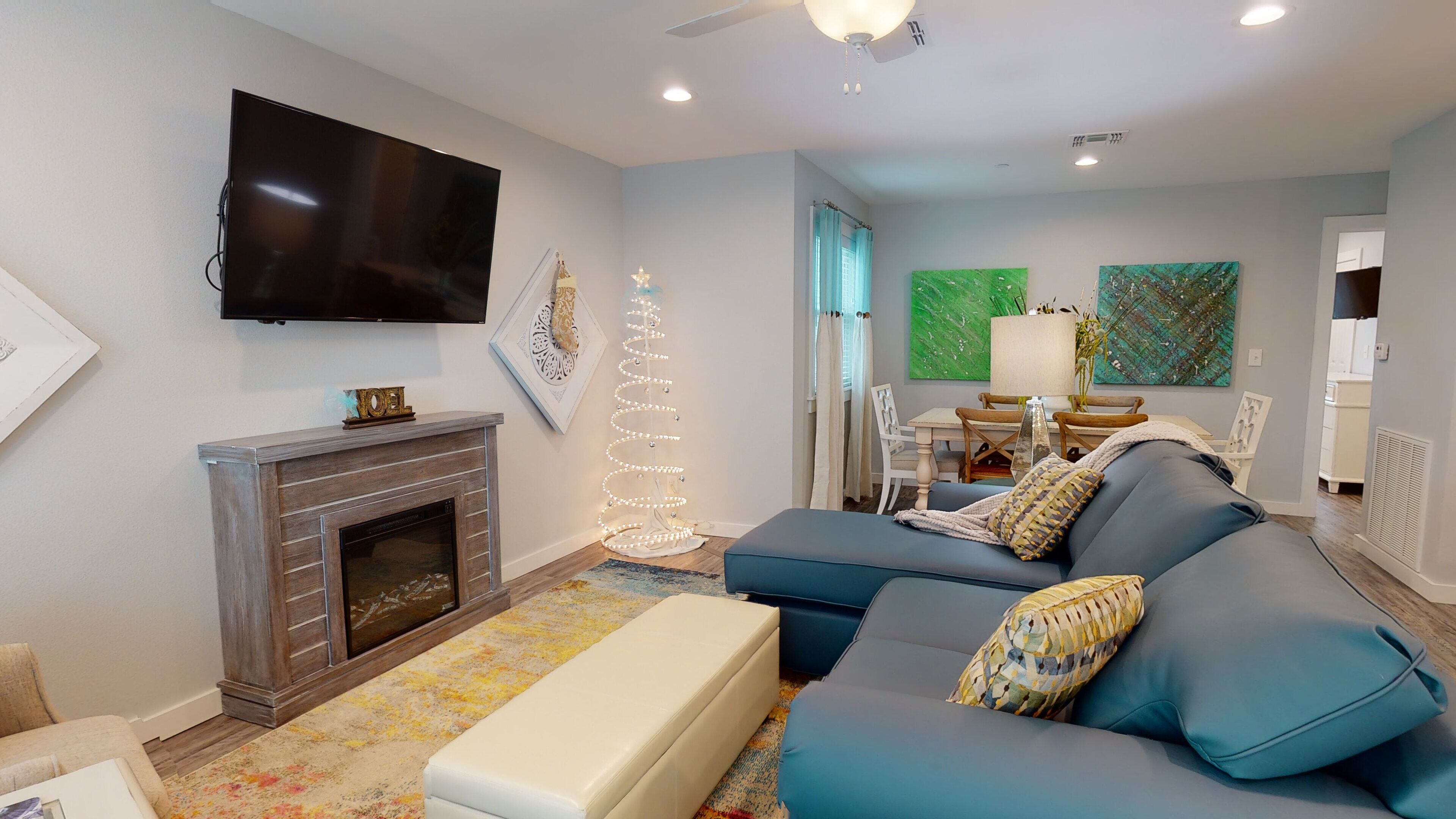 Una sala de estar con chimenea, televisor de pantalla plana, sofá azul y zona de comedor con mesa y sillas.