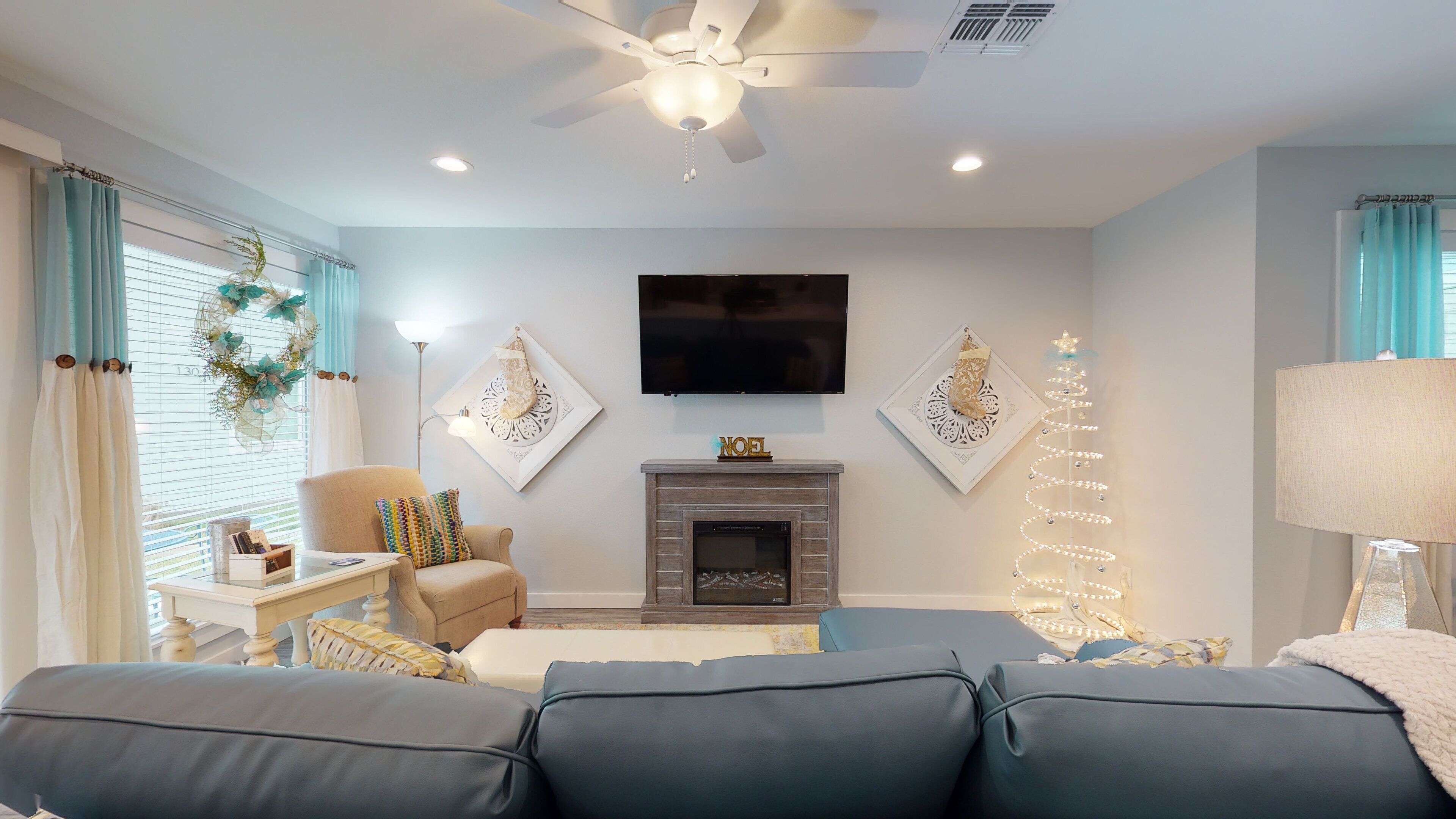 A living room with a fireplace, a television, and a Christmas tree.