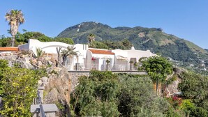 Una villa costera con una escalera de piedra que lleva a un edificio blanco con techo de tejas rojas.