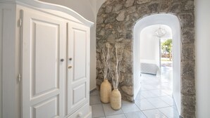 Un pasillo con pared de piedra, una puerta blanca y dos jarrones tejidos.